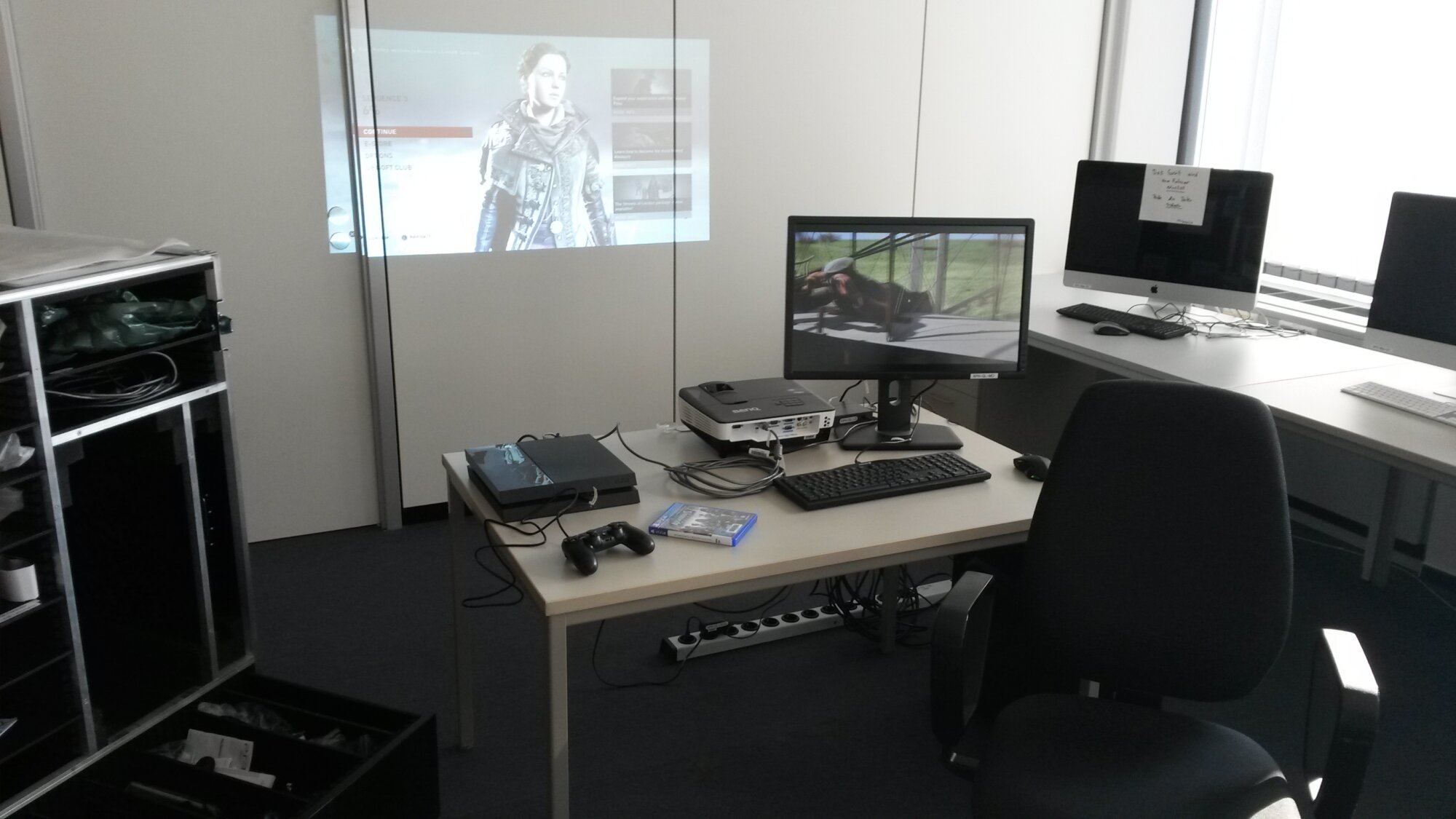 Wesentliche Bestandteile des GameLab in der Public History an der Universität Hamburg zeigt die aufgebaute Aufzeichnungssituation. Im Hintergrund ein Beamerbild von Assassin's Creed Syndicate auf der Playstation 4. Auf dem Monitor mit dem Aufzeichnungs-PC eine Videodatei. Links steht ein kompaktes Transport-Case von Konzert-Qualität, in dem alle Bestandteile mobil verstaut werden können.
