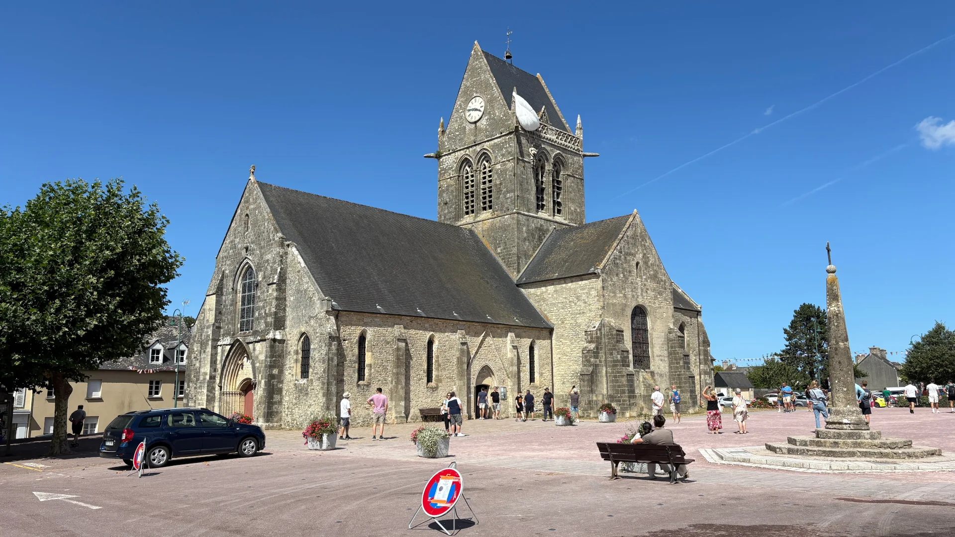 Die Kirche von Sainte-Mère-Église im Sommer 2026. Am Kirchturm erinnert bis heute ein Fallschirm an den US-Fallschirmjäger John Steele. Foto: André Eymann.
